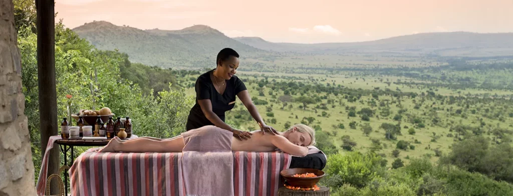 woman has a spa treatment on her deck with endless views of the Serengeti at Kleins camp