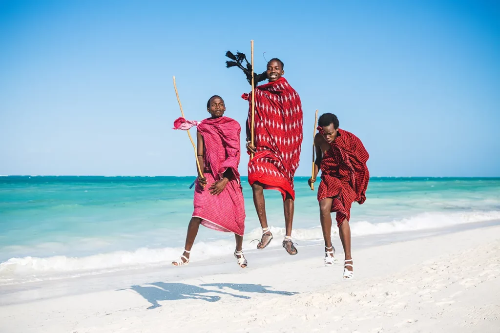 Masai Boys in red dress jumping on the beach in Zanzibar